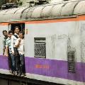 Men standing in the open door of a moving train in India